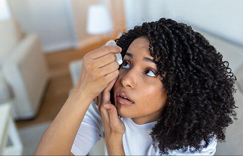 curly hair woman using eye drops